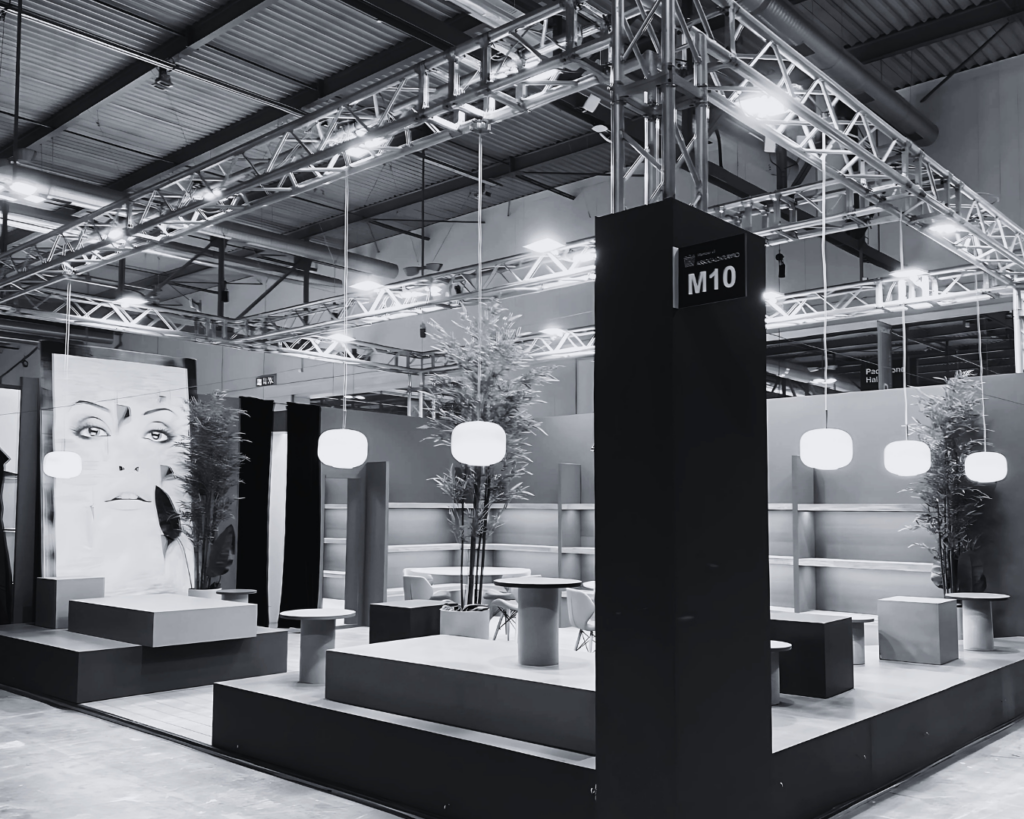 Stand fieristico dal design moderno con illuminazione sospesa e strutture modulari.