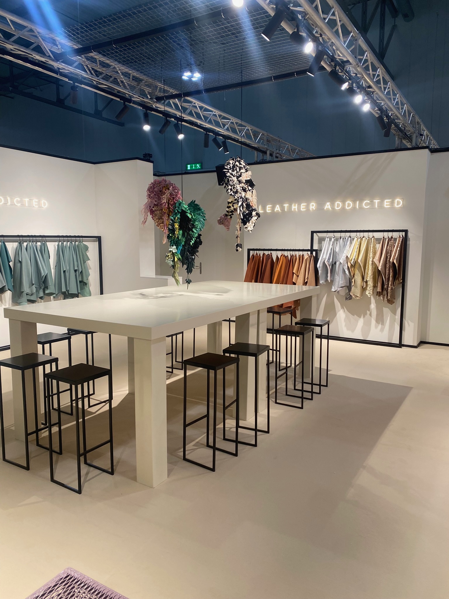 Tavolo alto bianco, sgabelli neri e campionari di pelli nello stand Leather Addicted a Lineapelle.