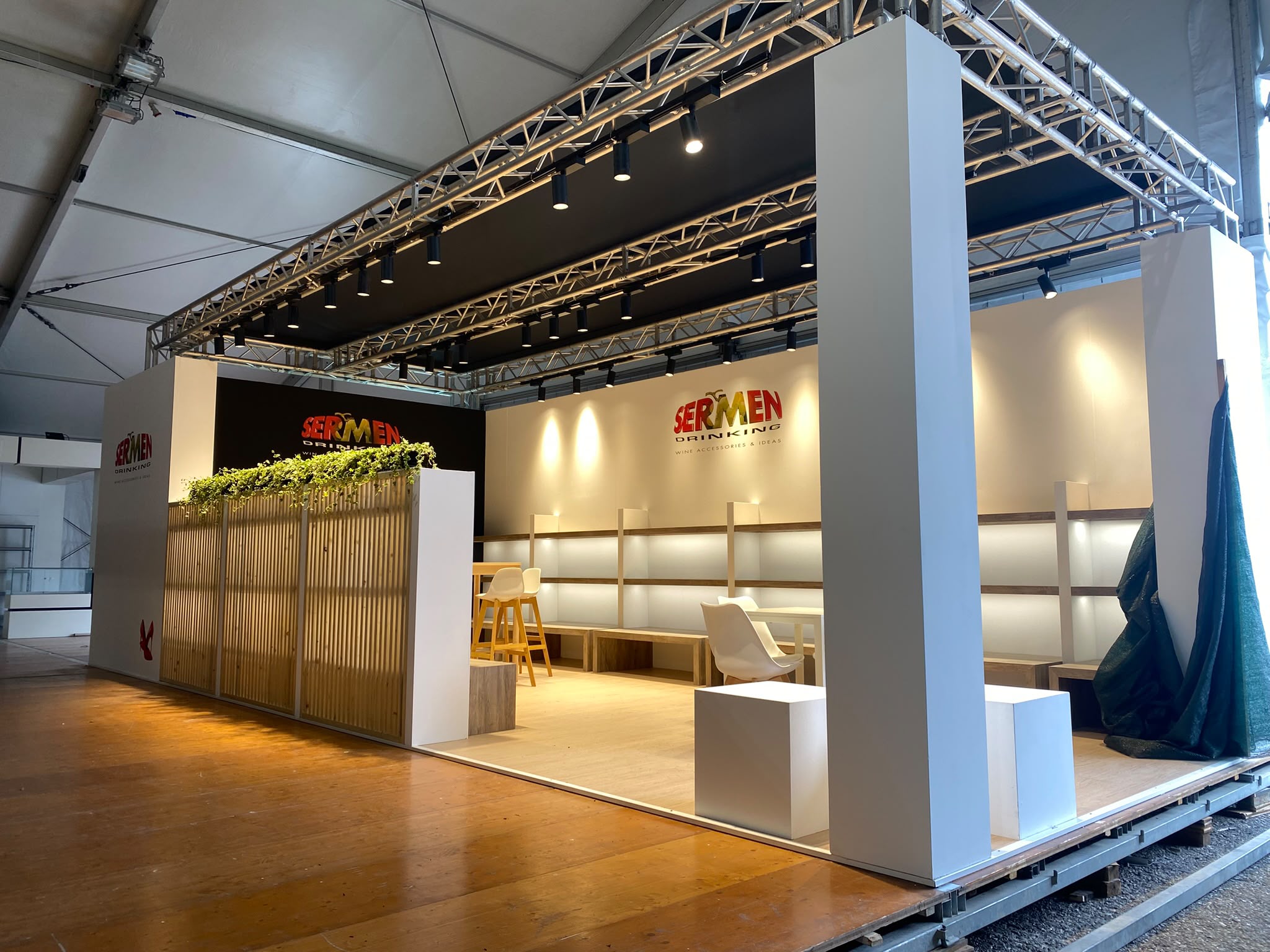 Stand Sermen Drinking a Vinitaly 2026, con ingresso aperto, pareti espositive e banco in legno.